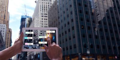 person holding tablet in front of skyscraper