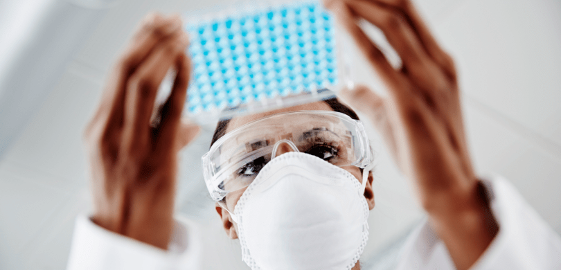 Doctor wearing mask and goggles holding a tray of vials