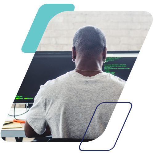 Image of a person coding on dual monitors masked by a parallelogram