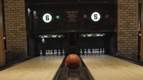 Image of two bowling lanes with  ball coming up the center