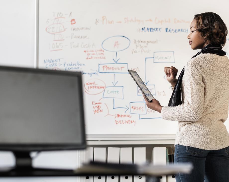 black woman on tablet in front of whiteboard 