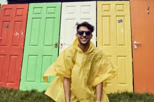 man in raincoat in front of colored doors