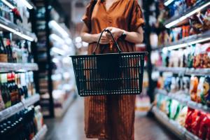 Color photo of woman shopper with grocery basket standing in a store aisle