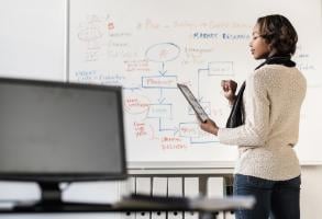 black woman on tablet in front of whiteboard 