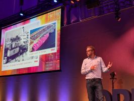 Dries on stage, talking about Rotterdam and its history, and the lessons for the Drupal community