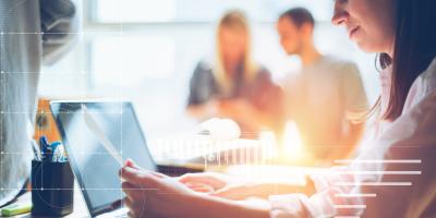woman looking at paper in front of laptop screen