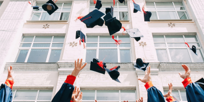 College graduates throwing black and orange caps into the air