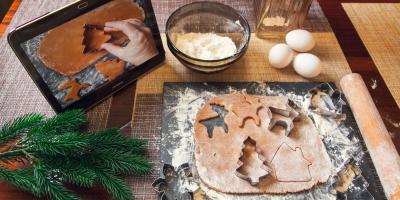 Baking station with cookie dough and cutters, rolling pin, eggs, flour and a tablet showing the recipe