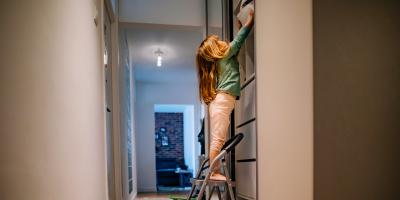 Child on step stool reaching for storage bin on high shelf