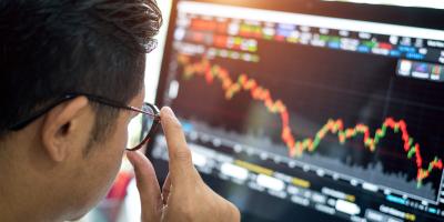 Color photo of man looking at a graph on a computer monitor 