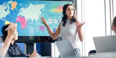 Woman gesticulating at world map chart in conference room