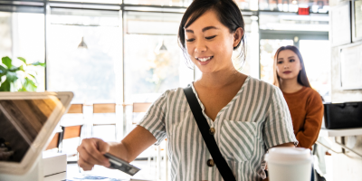 Color photo of young woman paying at a cafe with a credit card