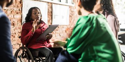 Businesswoman in wheelchair leading group discussion in creative office