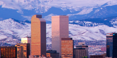 Downtown Denver skyline at dusk with snow-capped Rocky Mountains in the background