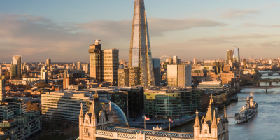 London skyline at sunset featuring Tower Bridge and The Shard skyscraper over the Thames River.