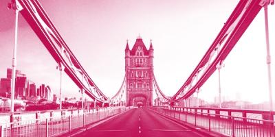 Pink-tinted view of Tower Bridge in London from the roadway perspective, showing the iconic Gothic towers and suspension cables.