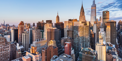 Manhattan skyline with sunlit skyscrapers at golden hour under blue sky