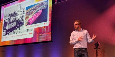 Dries on stage, talking about Rotterdam and its history, and the lessons for the Drupal community
