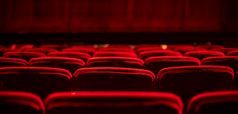 Red velvet theater seats in front of a stage