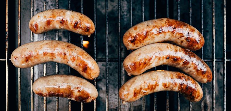 Six sausages on a barbecue grill