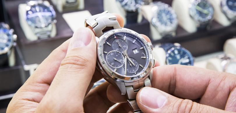 Close-up of hands holding a watch with watches in background