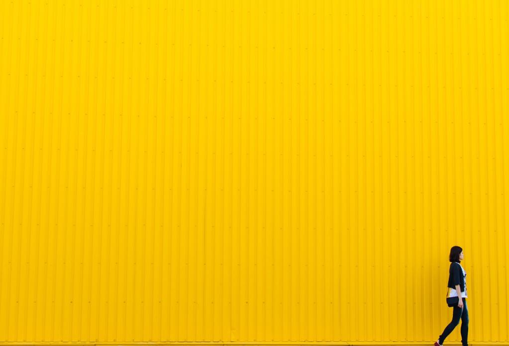 person walking in front of yellow wall