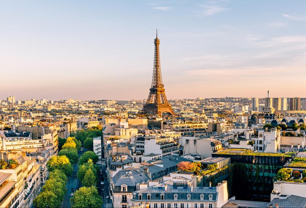 Aerial view of Paris cityscape with Eiffel Tower prominently featured at sunset