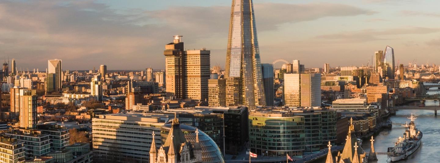 London skyline at sunset featuring Tower Bridge and The Shard skyscraper with Thames River