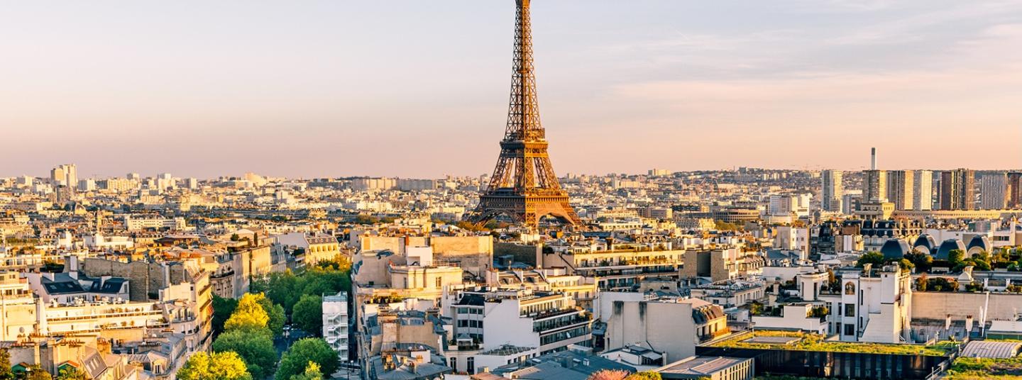 Aerial view of Paris cityscape with Eiffel Tower prominently featured at sunset