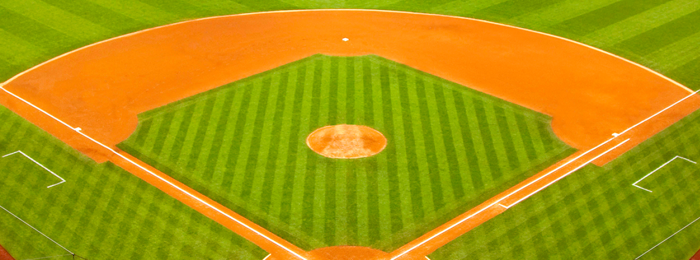 Aerial view of a baseball diamond with bright orange base paths and green grass