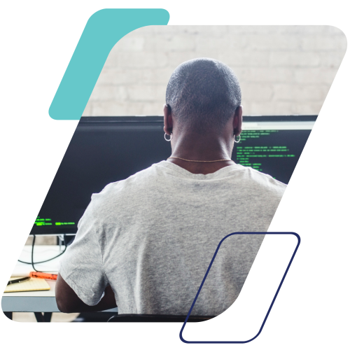 Image of a person coding on dual monitors masked by a parallelogram