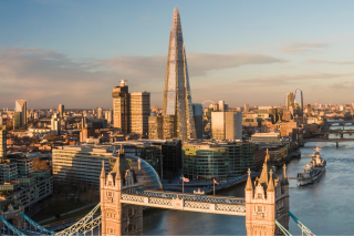 London skyline at sunset featuring Tower Bridge and The Shard skyscraper over the Thames River.