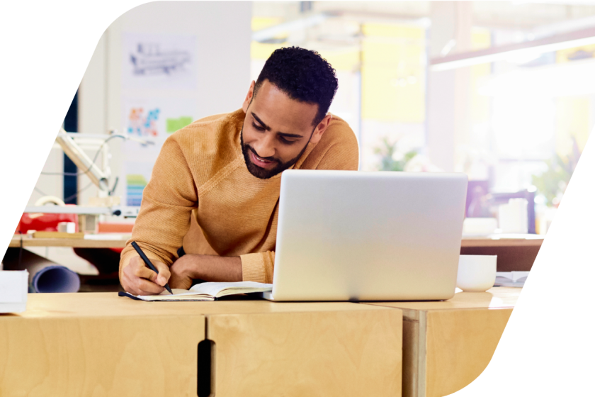 image of a person taking notes looking at laptop masked by a parallelogram