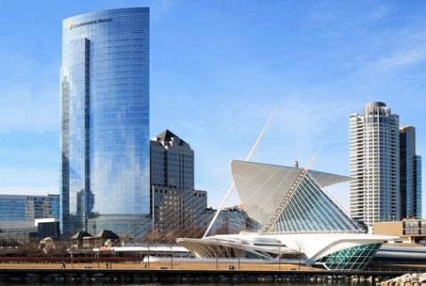 Milwaukee skyline with modern skyscrapers and distinctive white angular building under blue sky.