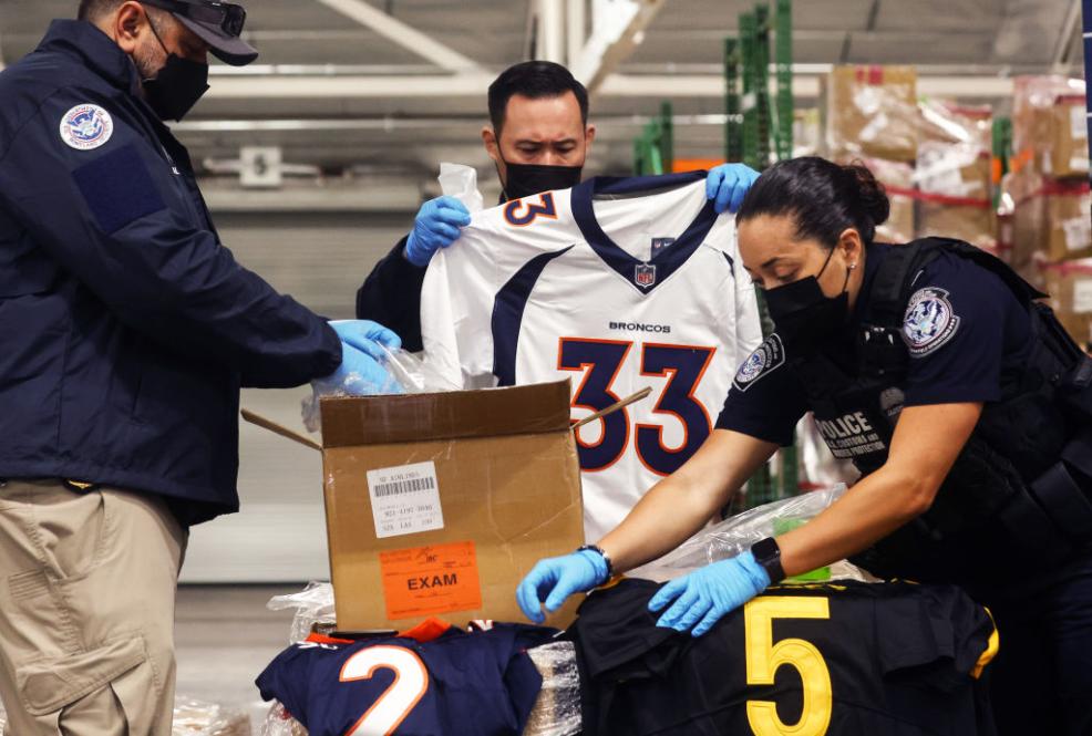 Color photo of U.S. Customs and Border Patrol seizing counterfeit NFL merchandise