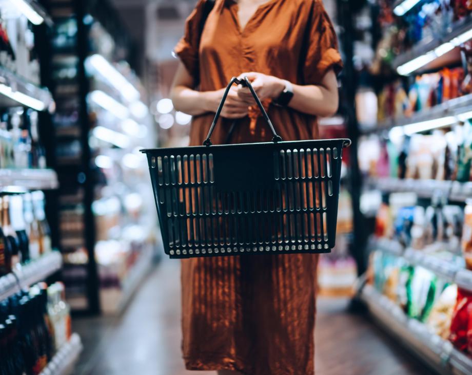 Color photo of woman shopper with grocery basket standing in a store aisle