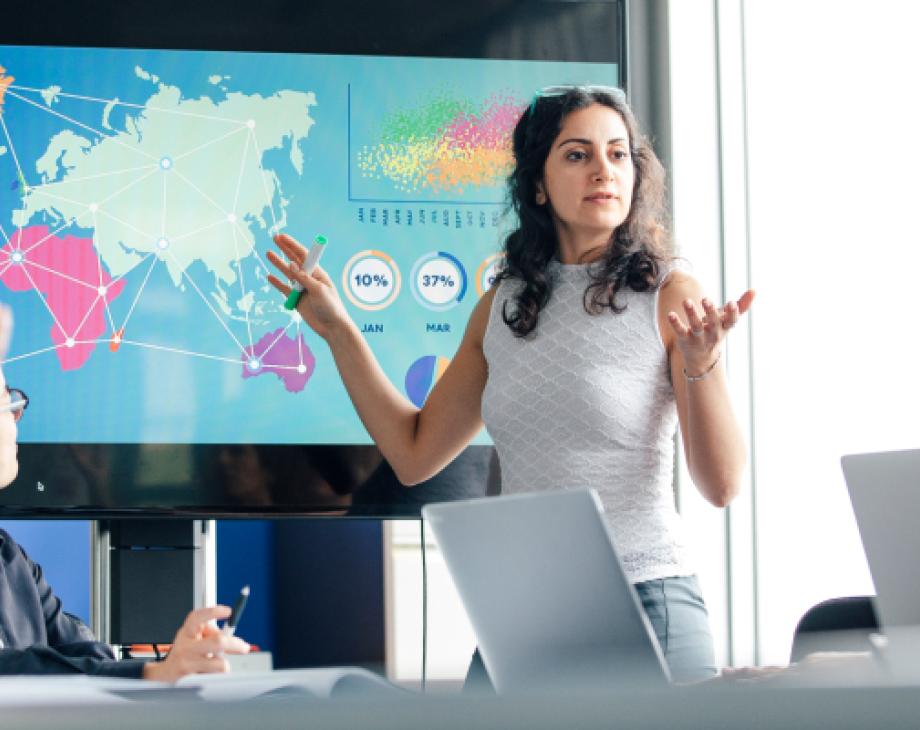 Woman gesticulating at world map chart in conference room