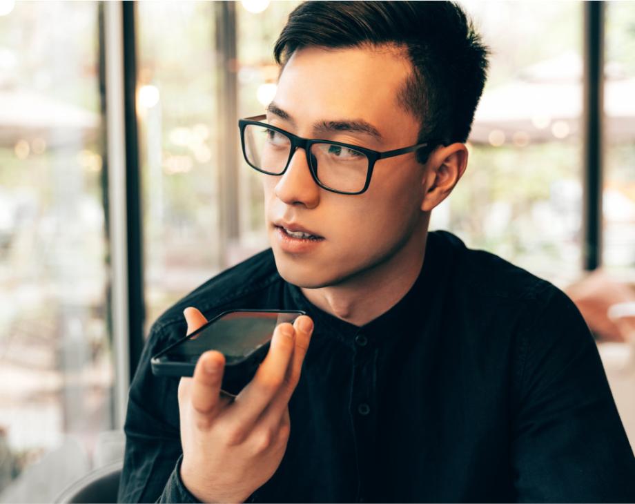 Color photo of bespectacled Asian man talking into a mobile phone
