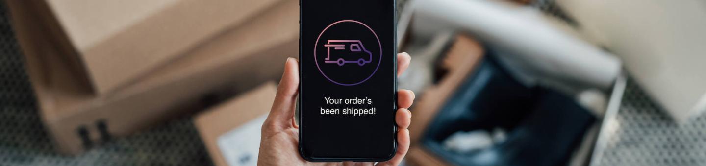 Smartphone with delivery message on screen in front of parcels