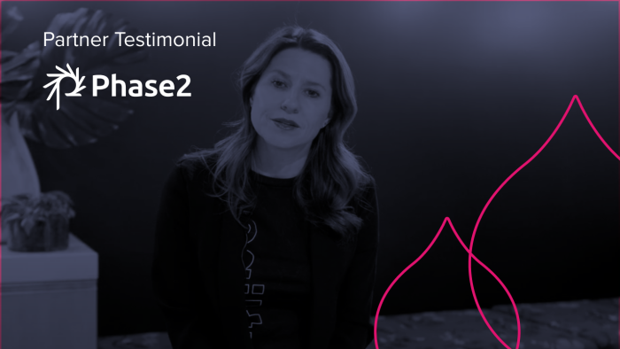 image from the video of a woman talking to the camera overlaid with a navy blue and the words "Partner Testimonial" with the Phase 2 logo under it