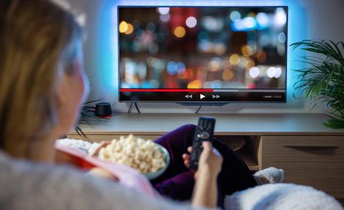 Woman with popcorn and remote in front of tv